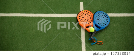 Padel paddles and a ball set on a green court for play Padel paddles and a ball set on a green court for play 137328014