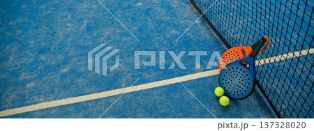 Padel equipment is on the court with tennis balls close by Padel equipment is on the court with tennis balls close by 137328020