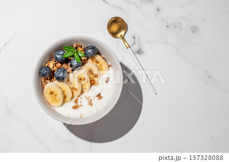 Natural greek yogurt with granola, blueberry and banana in a bowl on a marble background Natural greek yogurt with granola, blueberry and banana in a bowl on a marble background 137328088