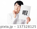 暇と書かれた紙を持ち暇そうに佇む白いシャツを着たシニア女性 137328125