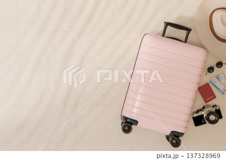 Top view of pink luggage suitcase with camera, hat, passport, boarding pass and sunglasses on floor. 137328969