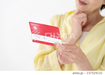 通帳を見て悩む女性　手元 137329132