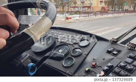 Bus driver holding steering wheel and driving in the city center Bus driver holding steering wheel and driving in the city center 137329889