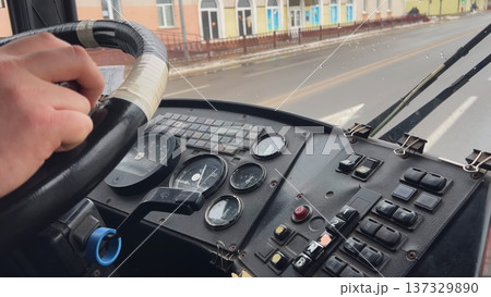 Bus driver holding steering wheel and driving on a wet road 137329890