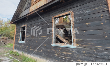 Charred wooden house with broken windows showing devastation after fire 137329891