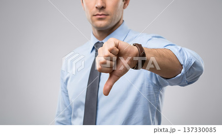 Businessman giving a thumbs down gesture, expressing disapproval or negativity in a professional setting Businessman giving a thumbs down gesture, expressing disapproval or negativity in a professional setting 137330085
