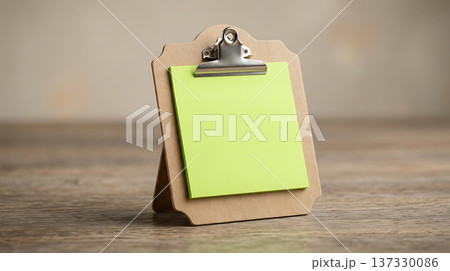 Blank green sticky note on a wooden clipboard with a metal clip, ready for messages 137330086
