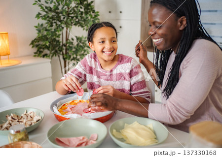 Mother and daughter bonding making homemade pizza together 137330168