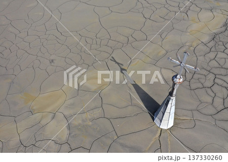 Aerial view of a sinking church in a decanting lake, tower with cross raising over mud, 137330260
