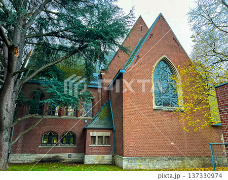 Gothic style red brick church surrounded by trees captured from street 137330974