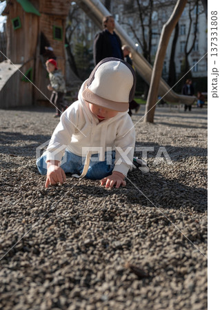 Toddler playing on gravel playground in sunny park Toddler playing on gravel playground in sunny park 137331808