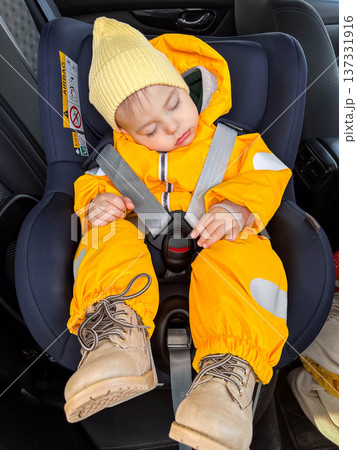 Sleeping baby in car seat wearing yellow winter snowsuit Sleeping baby in car seat wearing yellow winter snowsuit 137331916