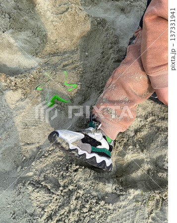 Child sneaker in beach sand with toy shovel Child sneaker in beach sand with toy shovel 137331941