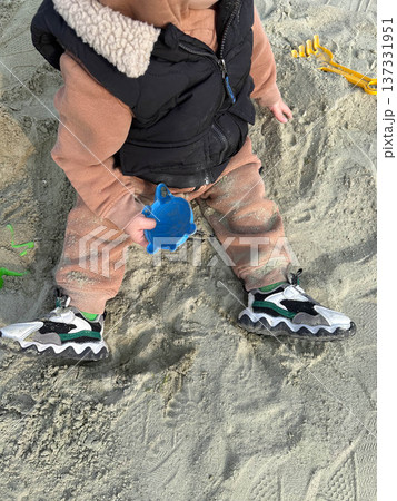 Toddler playing in sandbox holding blue sand mold 137331951