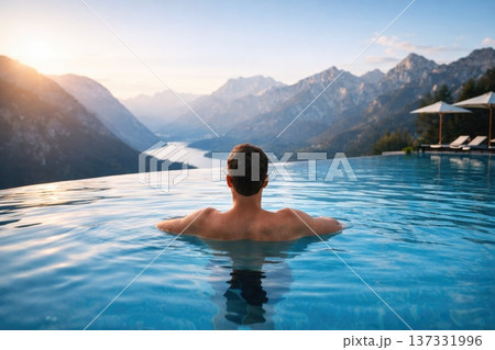 Man relaxing in infinity pool with breathtaking mountain and lake view symbolizing luxury travel and wellness Man relaxing in infinity pool with breathtaking mountain and lake view symbolizing luxury travel and wellness 137331996