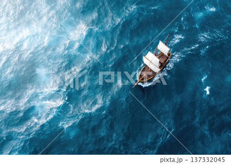 Small sailboat navigating deep blue ocean waves from aerial perspective Small sailboat navigating deep blue ocean waves from aerial perspective 137332045
