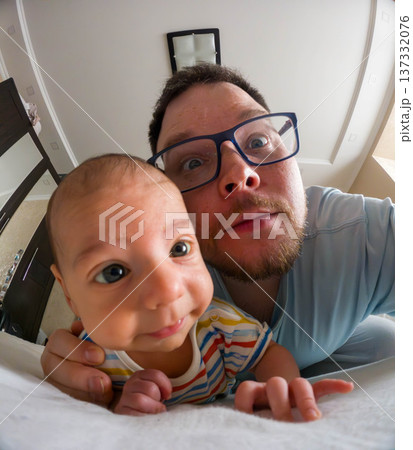 Playful father and baby selfie on bed at home 137332076