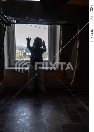 Toddler silhouette reaching toward window at home Toddler silhouette reaching toward window at home 137332085