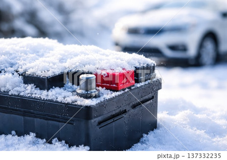 Car battery covered with snow in winter conditions with blurred vehicle in background 137332235