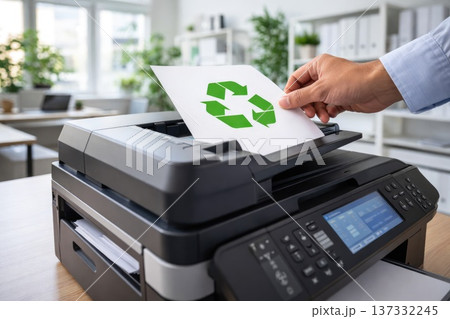 Hand placing paper with recycling symbol into modern office printer for eco concept 137332245