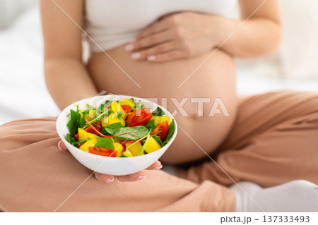 Closeup of pregnant woman holding bowl of fresh vegetable salad at home 137333493