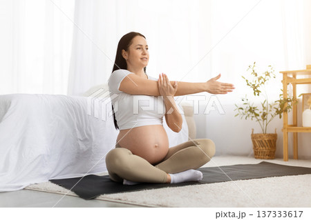 Pregnant woman practicing gentle prenatal stretching exercise on yoga mat at home Pregnant woman practicing gentle prenatal stretching exercise on yoga mat at home 137333617
