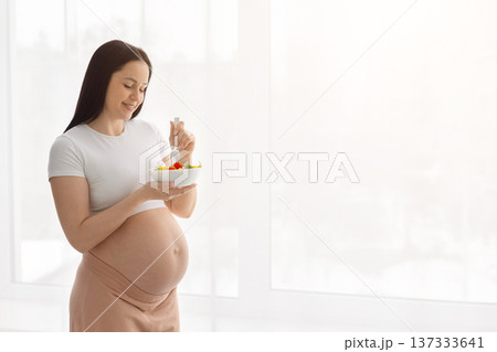 Pregnant woman eating fresh vegetable salad at home. Healthy prenatal nutrition Pregnant woman eating fresh vegetable salad at home. Healthy prenatal nutrition 137333641