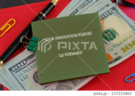 Olive note inspiring progress rests on US currency, with a pen clips on a red desk Olive note inspiring progress rests on US currency, with a pen clips on a red desk 137333863