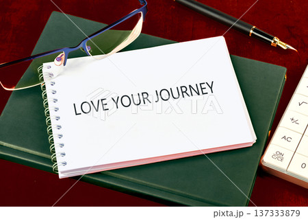LOVE YOUR JOURNEY notebook on dark green book, with glasses, fountain pen, and calculator on a deep red table LOVE YOUR JOURNEY notebook on dark green book, with glasses, fountain pen, and calculator on a deep red table 137333879