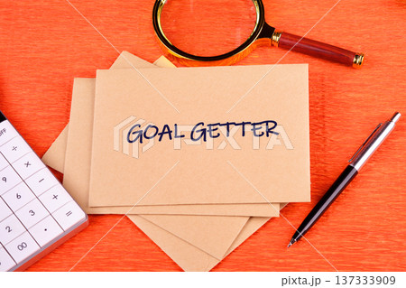 Goal Getter envelopes on orange desk, with calculator, magnifying glass, pen suggests financial planning Goal Getter envelopes on orange desk, with calculator, magnifying glass, pen suggests financial planning 137333909