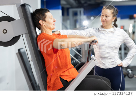 Senior woman exercising chest press with personal trainer Senior woman exercising chest press with personal trainer 137334127