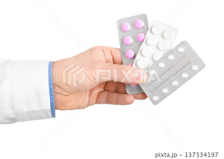 Doctor's hand holding three blister packs of different pills isolated on a white background. Concept of pharmacy, prescription, and healthcare treatment. High quality photo Doctor's hand holding three blister packs of different pills isolated on a white background. Concept of pharmacy, prescription, and healthcare treatment. High quality photo 137334197