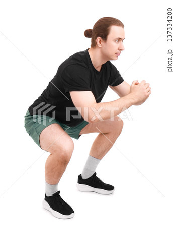 Side view of a fit man performing squat exercises isolated on white. Sporty male athlete with hair bun training legs and glutes during a workout. High quality photo Side view of a fit man performing squat exercises isolated on white. Sporty male athlete with hair bun training legs and glutes during a workout. High quality photo 137334200