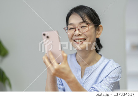 スマートフォンの画面を見る笑顔の50代後半の女性 スマートフォンの画面を見る笑顔の50代後半の女性 137334517
