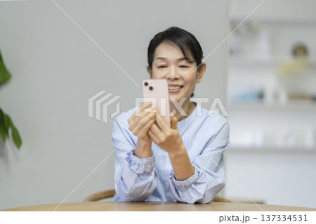 スマートフォンの画面を見て微笑む50代後半の女性 スマートフォンの画面を見て微笑む50代後半の女性 137334531
