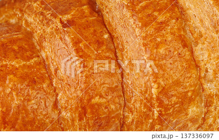 Extreme close up of crispy croissant texture. Macro shot of golden brown flaky puff pastry surface. Extreme close up of crispy croissant texture. Macro shot of golden brown flaky puff pastry surface. 137336097