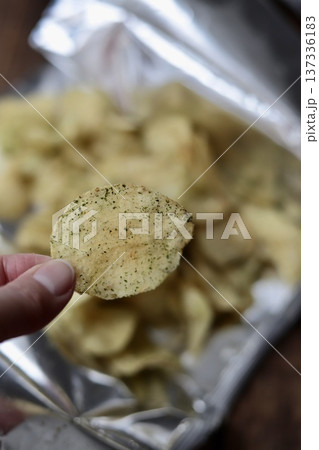 パーティー開けしたポテトチップスを一枚持ち上げた指先 137336183
