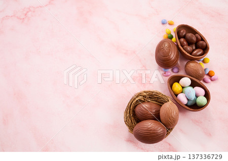 Chocolate easter eggs and nests on pink marble Chocolate easter eggs and nests on pink marble 137336729
