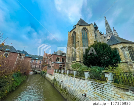 Gothic church and historic town houses in Leuven with canal under blue sky 137336986