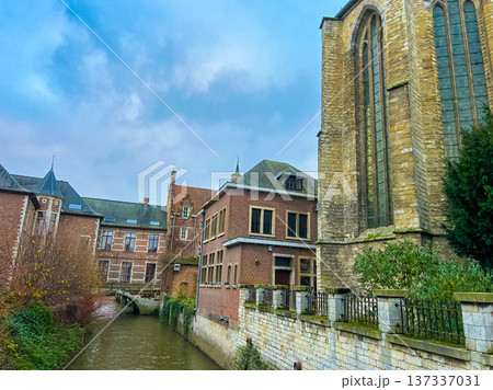 Gothic church and historic town houses in Leuven with canal under blue sky 137337031