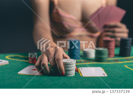 Woman in Casual Attire Engages in Intense Card Game with Poker Chips and Cards on Green Felt Table, Capturing Strategic Moment of Play Woman in Casual Attire Engages in Intense Card Game with Poker Chips and Cards on Green Felt Table, Capturing Strategic Moment of Play 137337139