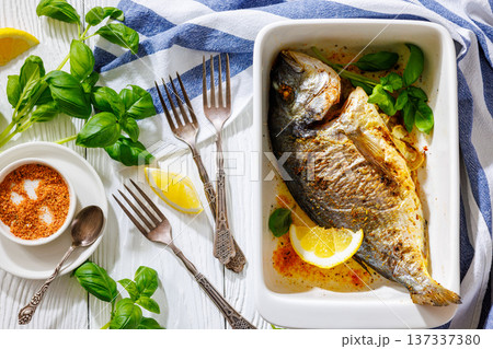 Baked whole dorada fish with lemon and basil 137337380