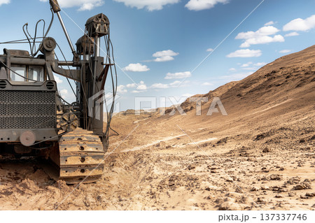 A pile driving rig is engaged in work on a rough terrain under a clear sky. The machine prepares the ground for an upcoming construction project A pile driving rig is engaged in work on a rough terrain under a clear sky. The machine prepares the ground for an upcoming construction project 137337746