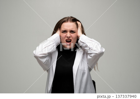 Stressed woman covering ears, screaming in frustration, suffering from headache, noise, anger, and anxiety Stressed woman covering ears, screaming in frustration, suffering from headache, noise, anger, and anxiety 137337940