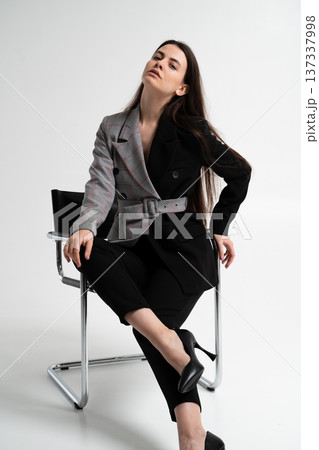 Woman with conceptual duality blazer merging classic plaid and solid black, creating a split design showcasing a professional, confident, and modern fashion statement 137337998