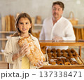 Girl in bakery chooses bread, considers various product options. 137338471