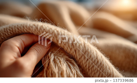 柔らかなベージュのニット生地に優しく触れる手のクローズアップ 137339686