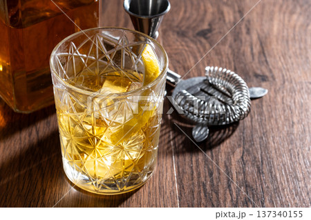 Rusty Nail Cocktail with Lemon Peel in Crystal Glass 137340155