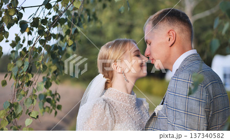 Romantic newlyweds sharing a tender moment under a birch tree, symbolizing love and new beginnings on their wedding day Romantic newlyweds sharing a tender moment under a birch tree, symbolizing love and new beginnings on their wedding day 137340582