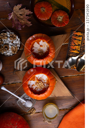 baked pumpkin cream coup with cream and nuts served in pumpkins. served at wooden rural brown table for 2 person . cooking recipe. healthy life concept. flat lay baked pumpkin cream coup with cream and nuts served in pumpkins. served at wooden rural brown table for 2 person . cooking recipe. healthy life concept. flat lay 137341690